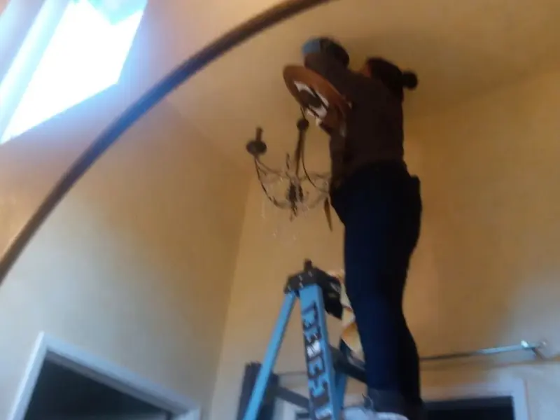 Electrician installing a chandelier in a Taylor Lake Village residence